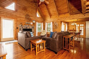 Spacious, sunlit living room with vaulted ceilings, a crackling fireplace, and plush seating for ultimate relaxation.