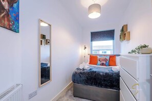 Bright and stylish bedroom with a cosy bed, vibrant cushions, and natural light – a perfect retreat for relaxation!