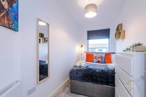 Bright and stylish bedroom with a cosy bed, vibrant cushions, and natural light – a perfect retreat for relaxation!
