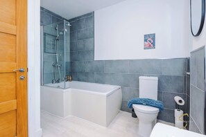 Stylish and contemporary bathroom featuring a sleek bathtub-shower combo, modern tiling for a refreshing stay!