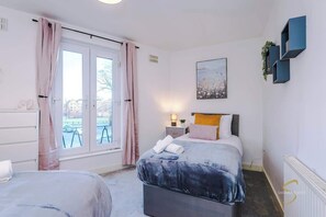 Spacious and inviting bedroom with a comfy bed, bright natural light from the window, and elegant wall art for a relaxing stay!