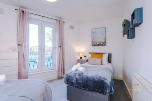 Spacious and inviting bedroom with a comfy bed, bright natural light from the window, and elegant wall art for a relaxing stay!