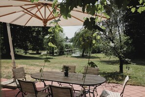 Große Terrasse mit Blick in den weitläufigen Garten und auf den See.