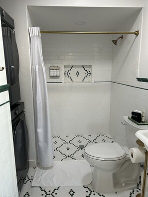 Fully tiled shower with Beekman 1802 shower amenities and full sized washer and dryer