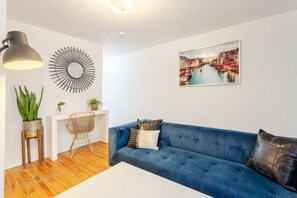 Living Room: Bold blue sofa, elegant wall art, and a stylish writing nook that blends form and function