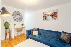 Living Room: Bold blue sofa, elegant wall art, and a stylish writing nook that blends form and function