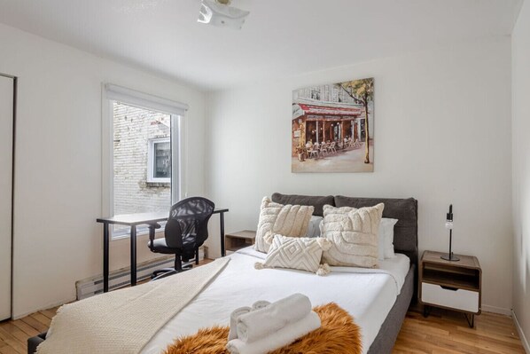Bedroom #1: Sunlit and serene, with layered textures, a plush bed, and a work desk by the window.