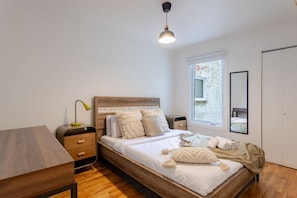 Bedroom 1 – Queen bed with warm lighting and natural wood floors
