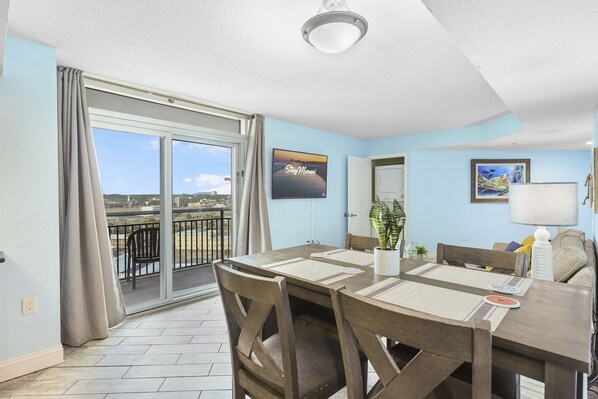 Gather, dine, and unwind in this bright and spacious open-concept living area featuring a large dining table, cozy seating, and access to a private balcony with scenic views—perfect for your Myrtle Beach vacation!