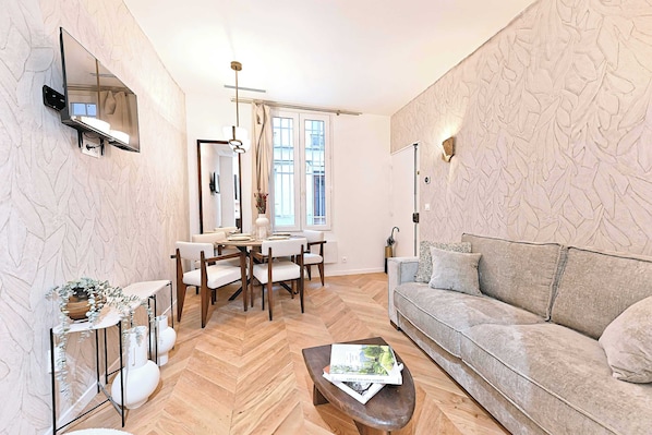 Salon avec canapé lit, TV et espace repas pour 4 personnes
