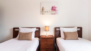 A calm and cozy twin bedroom, ideal for friends or family, with soft lighting and neutral tones. #RelaxingRetreat #FamilyFriendly