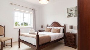 Unwind in this elegant bedroom featuring timeless wood furniture and serene natural light. #TimelessStyle #CozyStay