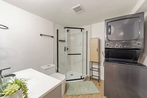 A beautiful and functional bathroom, contains washing machine and dryer