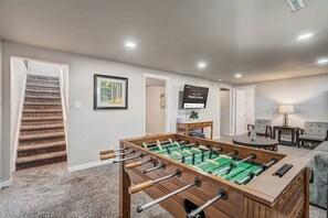 Enjoy game nights in the spacious downstairs living area, complete with a foosball table, Smart TV, and plenty of seating for fun and relaxation.