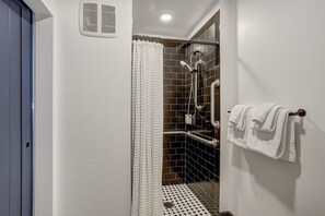 Modern bathroom with bold black tile and chic finishes, offering a spa-like atmosphere for a refreshing experience.