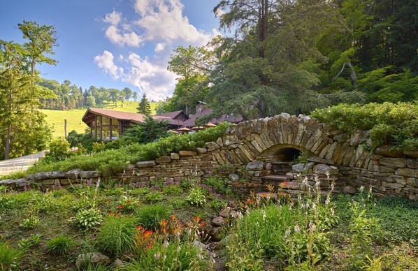Picturesque stone bridge surrounded by vibrant greenery and blooming flowers, offering a fairytale-like setting.