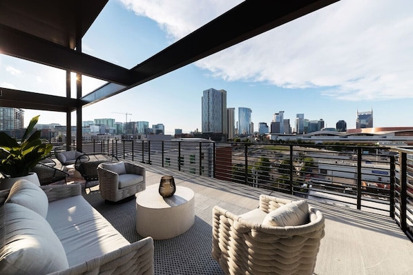 Stylish and inviting balcony with modern furnishings, lush greenery, and stunning city skyline views.