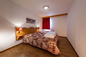 A charming bedroom with warm wooden accents and soft lighting for a restful night in the mountains.