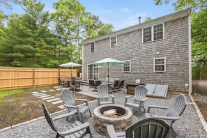 Backyard with dining table, seating area, firepit, grill, umbrellas & yard games