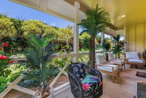 Lounge on the covered patio, offering comfortable seating and lush garden views.