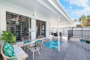  A generous patio features outdoor dining and furniture overlooking the pool and backyard.
