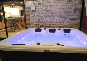 Jacuzzi privatif sous une pergola en bois, vue sur le domaine et les chevaux 