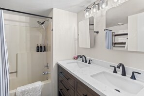 Remodeled guest bath w/ dual vanity and tub/shower combo. 