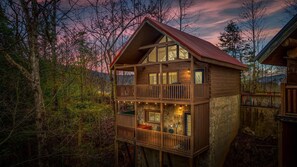 A view highlighting the cabin's multiple levels, featuring balconies with scenic views of the surrounding forest.