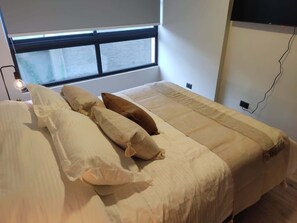 Cozy bedroom with plush bedding and a wall-mounted TV, perfect for relaxation after exploring the city.