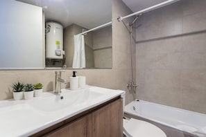 Relax in this modern bathroom featuring a sleek sink, shower, and cozy plants for a refreshing touch.
