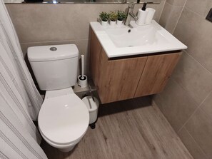 Refréscate y rejuvenece en este moderno baño, con una amplia ducha y todos los elementos esenciales para una estancia confortable."