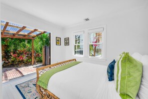 Serene queen primary bedroom featuring designer furnishings, high-end linens, and curated modern decor—open the French doors to the tropical patio and pool retreat.