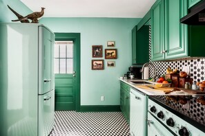 Bright and inviting kitchen with retro charm, featuring mint-green cabinets, a vintage stove, and a starry tile backsplash—a perfect space to cook and unwind