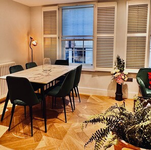 Bright open plan dining room with large marble table and six velour chairs 