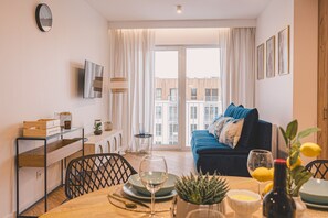 A chic living room in a loft style, featuring a wooden table that blends modernity and minimalism. This elegant space invites relaxation after beach strolls, offering the perfect setting for quality time with loved ones.