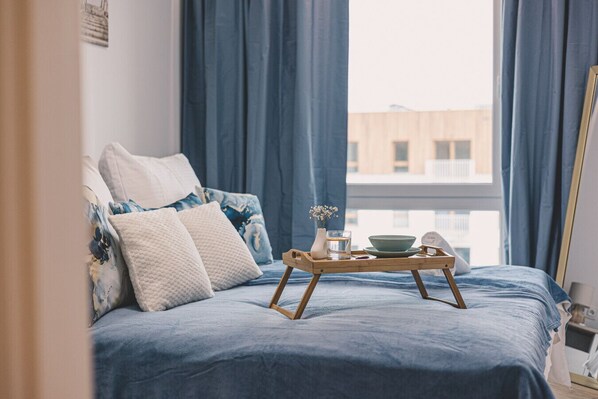 A cozy bedroom in a loft style, adorned with marine colors and beautiful artwork. The spacious, comfy bed promises restful nights, while the window view reminds you the beach is just 50 m away. Perfect for dreaming and serene mornings.