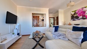 Seaside Orchid: A cozy T2 apartment in Câmara de Lobos with a beautifully designed living room featuring a lovely, plush sofa. Enjoy comfort and style in this inviting coastal retreat.