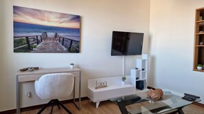 Seaside Orchid: A cozy T2 apartment in Câmara de Lobos with a beautifully designed living room featuring a plush sofa and a desk-friendly setup. Perfect for work and relaxation by the coast. #computerdesk