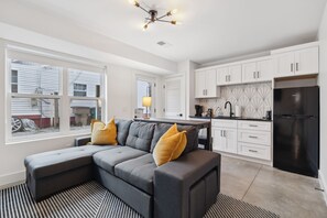 Living Room: Spacious living area with a wall-mounted TV, modern light fixtures, and a large sectional sofa for family gatherings.