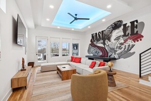 Living Room: Relax in style with this spacious living area featuring a bold, custom mural, cozy sectional, and a sleek entertainment setup.