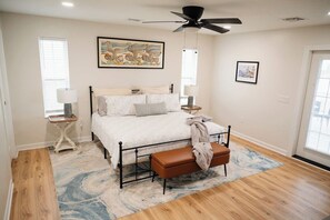 Spacious primary bedroom with a cozy king bed, stylish decor, and double doors leading to a beautiful wraparound porch—perfect for a relaxing retreat!