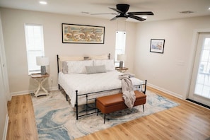 Spacious primary bedroom with a cozy king bed, stylish decor, and double doors leading to a beautiful wraparound porch—perfect for a relaxing retreat!