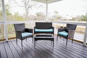 Relax on the waterfront porch with cozy wicker seating—perfect for morning coffee or evening conversations in a peaceful setting!