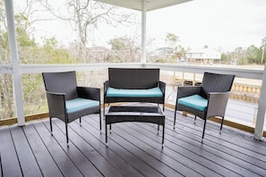 Relax on the waterfront porch with cozy wicker seating—perfect for morning coffee or evening conversations in a peaceful setting!