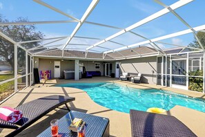 Ultimate outdoor retreat! This screened-in pool area features cozy lounge chairs, a hot tub, and multiple sitting areas.