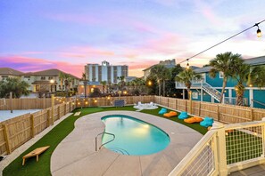 Private backyard oasis with heated pool, putt-putt, lounge chairs, hammock, outdoor kitchen, fire pit, and corn hole.