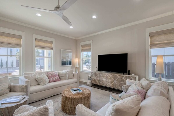 Living room: Main floor, 75” Smart TV, two couches, lounge chairs, ceiling fan, central heating and A/C, patio access