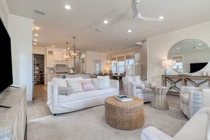 Living room: Main floor, 75” Smart TV, two couches, lounge chairs, ceiling fan, central heating and A/C, patio access