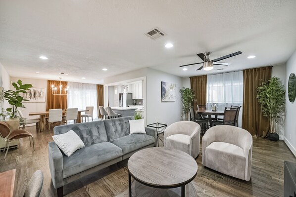 Unwind in the open-concept living room, featuring a sofa, smart TV, and a desk area. Ideal for gatherings, with board games and ample seating, creating a welcoming space for everyone to relax and connect.
