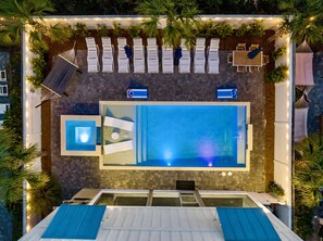 Private backyard oasis with heated pool, hot tub, lounge chairs, hammock, outdoor dining table, corn hole and a screened in outdoor kitchen, dining, and lounge area!